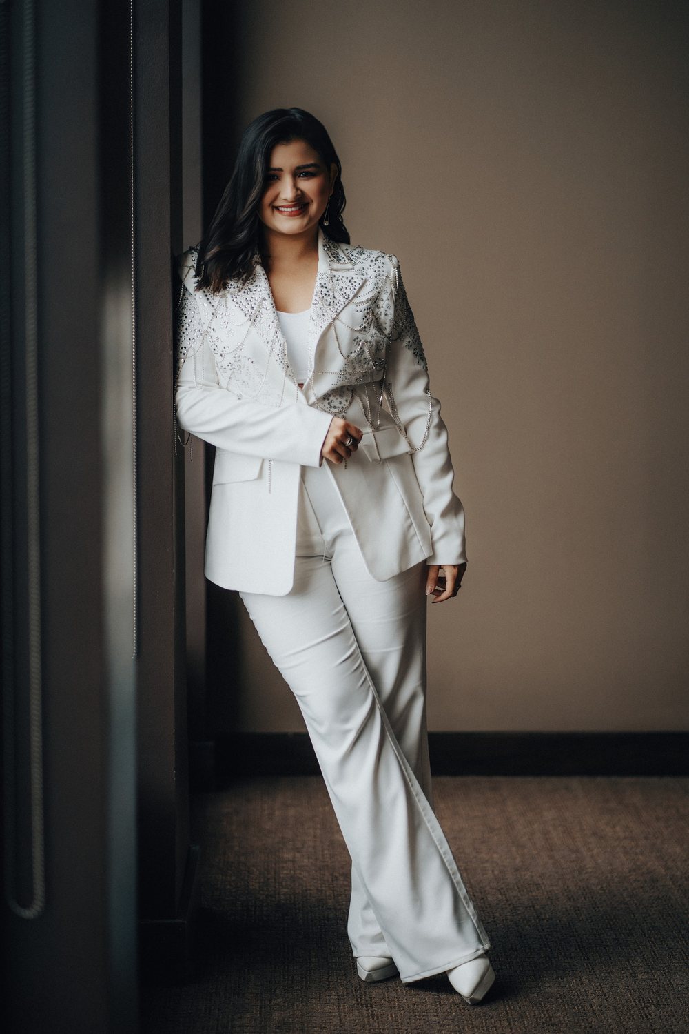 Mary Claudia Andrade de pie, sonriendo, con traje blanco